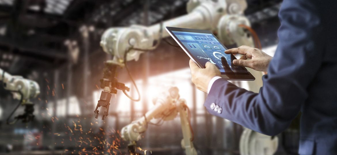 Manager industrial engineer using tablet check and control automation robot arms machine in intelligent factory industrial on real time monitoring system software. Welding robotics and digital manufacturing operation. Industry 4.0 concept
